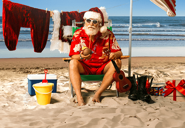 Ein Mann sitzt mit Santa Mütze am Strand und genießt seinen Sommerlotterie Gewinn